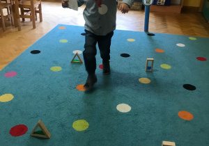 Chłopiec pokonuje tor przeszkód ustawiony na dywanie.
