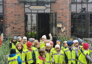 Dzieci ubrane w kamizelki odblaskowe stoją przed restauracją De Elefanta.