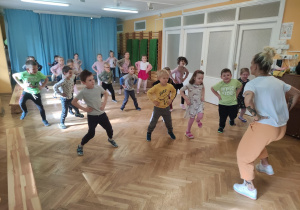 Dzieci z rękami na biodrach uczą się tańca podczas zajęć z zumby.