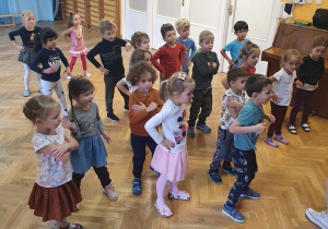 Dzieci powtarzają za panią prowadzącą kroki układu tanecznego na zajęciach zumby.
