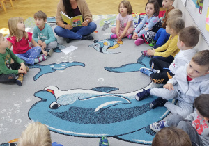 Dzieci siedzą w kole, a nauczycielka czyta im opowiadania o Wróbelku Elemelku, bohaterze projektu edukacyjnego.