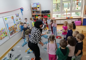 Dzieci wspólnie z Panią od angielskiego tańczą na dywanie do piosenki.