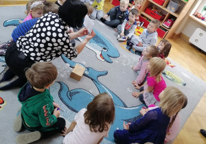 Dzieci siedzą w kole, a Pani od angielskiego pokazuje im obrazki na kartonikach.