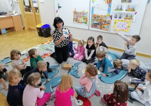 Dzieci siedzą w kole, a Pani od angielskiego pokazuje im obrazek parasolki.