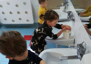 Chłopcy i dziewczynka próbują samodzielnie umyć rączki w łazience.