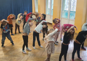 Dzieci ćwiczą układ taneczny na zajęciach z zumby przy szybkiej muzyce.
