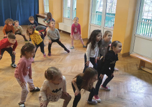 Dzieci ćwiczą układ taneczny na zajęciach z zumby przy szybkiej muzyce.