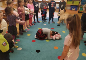 Dzieci ustawione w kole bawią się z misiami w zabawę ruchową "Stary niedźwiedź mocno śpi".