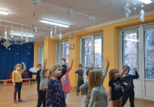 Dzieci tańczą do muzyki z podniesioną rączką do góry.