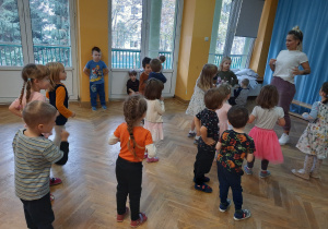 Dzieci uczą się nowego układu tanecznego, powtarzając ruchy za trenerką zumby.
