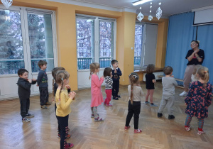 Dzieci wspólnie z trenerką zumby wykonują ćwiczenia do muzyki.