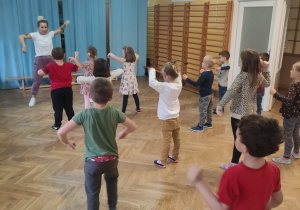 Dzieci tańczą podczas zajęć z zumby, naśladując ruchy instruktorki.