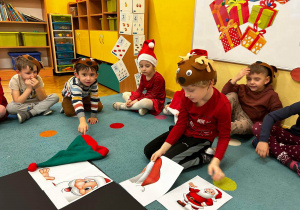 Dzieci siedzą na dywanie i układają puzzle Świętego Mikołaja XXL.
