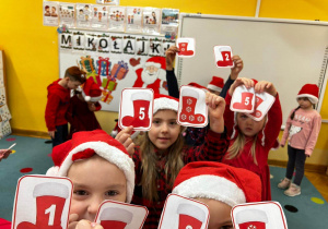 Zabawa matematyczno-ruchowa. Dzieci pokazują obrazki ze skarpetami Świętego Mikołaja.