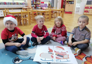 Trzech chłopców i dziewczynka prezentują ułożone przez siebie puzzle ze Świętym Mikołajem.
