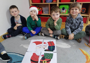 Czterech chłopców prezentuje ułożone przez siebie puzzle ze Świętym Mikołajem.