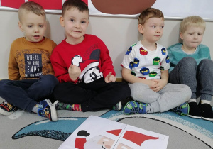 Czterech chłopców prezentuje ułożone przez siebie puzzle ze Świętym Mikołajem.