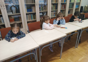 Dzieci przy stolikach wykonują pracę plastyczną - zakładkę do książki.