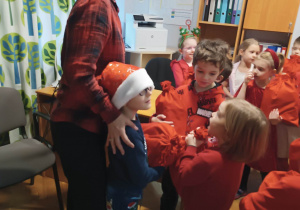 Dzieci stoją w gabinecie Pani dyrektor i odbierają prezenty od Świętego Mikołaja.
