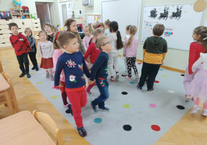Dzieci tańczą do muzyki w parach na dywanie.