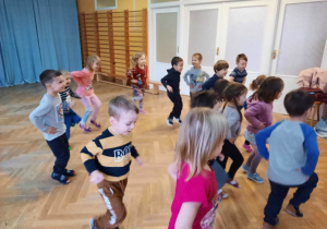 Dzieci powtarzają ruchy taneczne za trenerką zumby przy szybkiej muzyce.