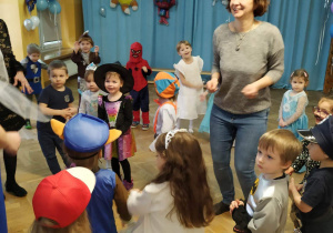 Dzieci wspólnie z Paniami tańczą na balu karnawałowym przebrane w różne stroje postaci z bajek.
