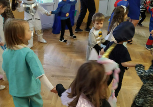 Dzieci przebrane w różne stroje wspólnie z Paniami tańczą w kole, a w środku pozostałe dzieci tańczą w małym kółku.