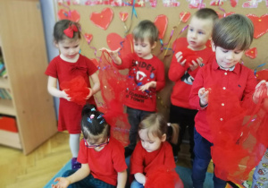 Dzieci pozują do zdjęcia trzymając w rączkach czerwone chusty.