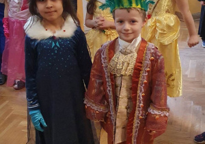 Dziewczynka z chłopcem przebrani za parę królewską pozuje do wspólnego zdjęcia.