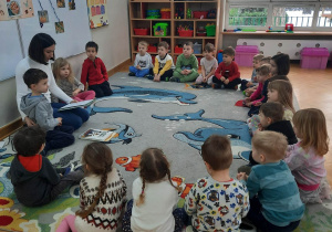 Akcja "Czytamy, głowy otwieramy", dzieci siedzą w kole i słuchają, jak mama ich kolegi czyta im różne opowiadania.