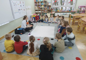Dzieci siedzą w półkolu i rozmawiają z prowadząca warsztaty LABOLO o ciśnieniu.