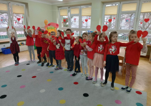 Dzieci pozują do grupowego zdjęcia z papierowymi sercami w rękach.