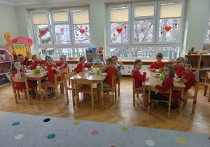 Dzieci siedzą przy stolikach i zajadają się pysznościami przygotowanymi z okazji walentynek.