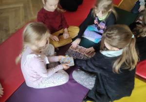 Dzieci siedzą na materacu i układają większy wzór z kafelków.
