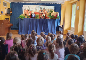 Dzieci siedzą na materacach i oglądają przedstawienie teatrzyku kukiełkowego pt. "Smok wawelski".