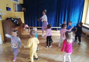 Dzieci w rozsypce na sali gimnastycznej tańczą dowolnie do ulubionej piosenki.